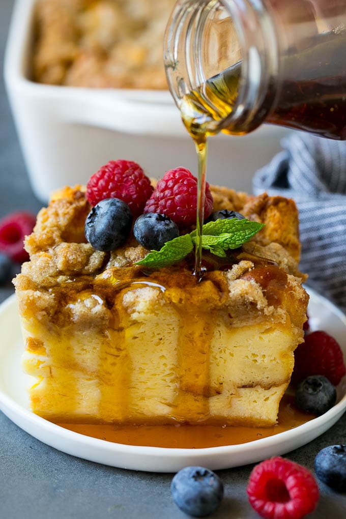French toast casserole, topped with fresh raspberries, blueberries, and a sprig of mint, drizzled with maple syrup.