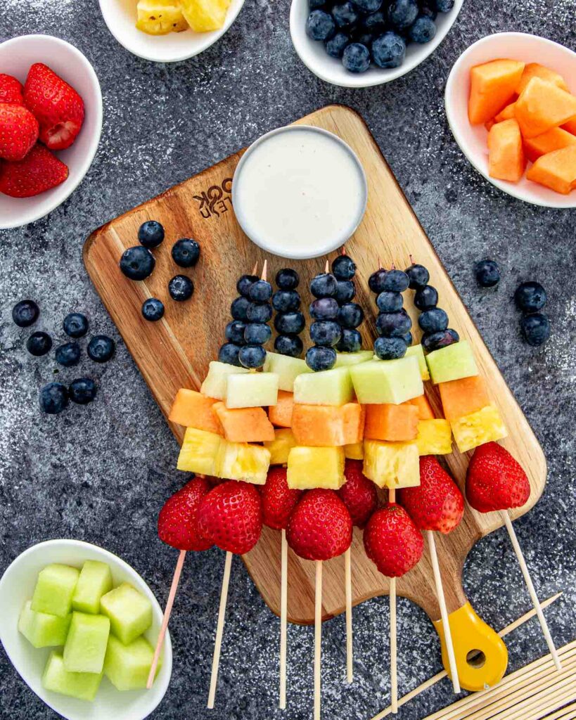 Assortments of fruit on stick with a side of you gust to dip it in