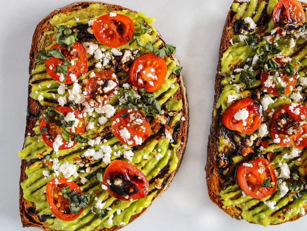 Avocado toast with cherry tomatoes and goat cheese with a drizzle of balsamic sauce