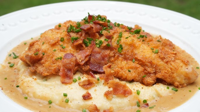 Catfish and grits with a gravy sauce, topped with bacon pieces and scallions.